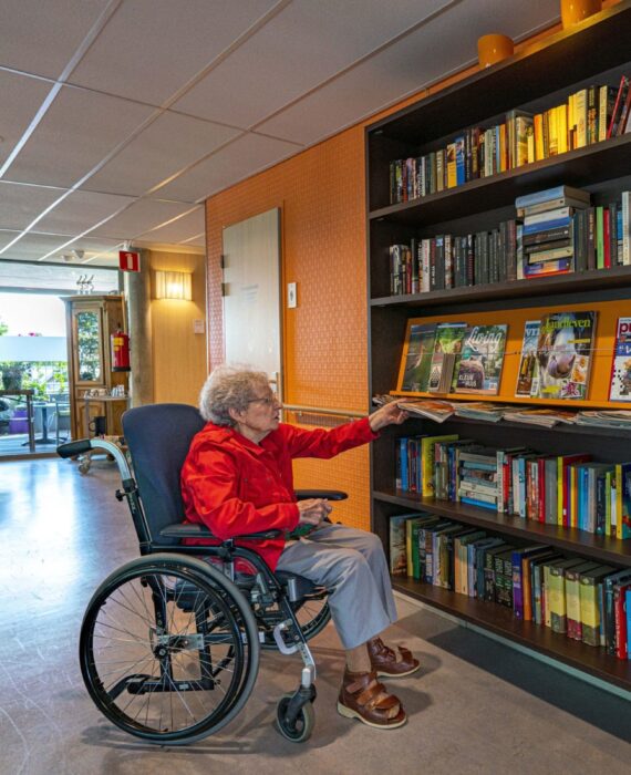 Mevrouw zoekt tijdschrift in boekenkast