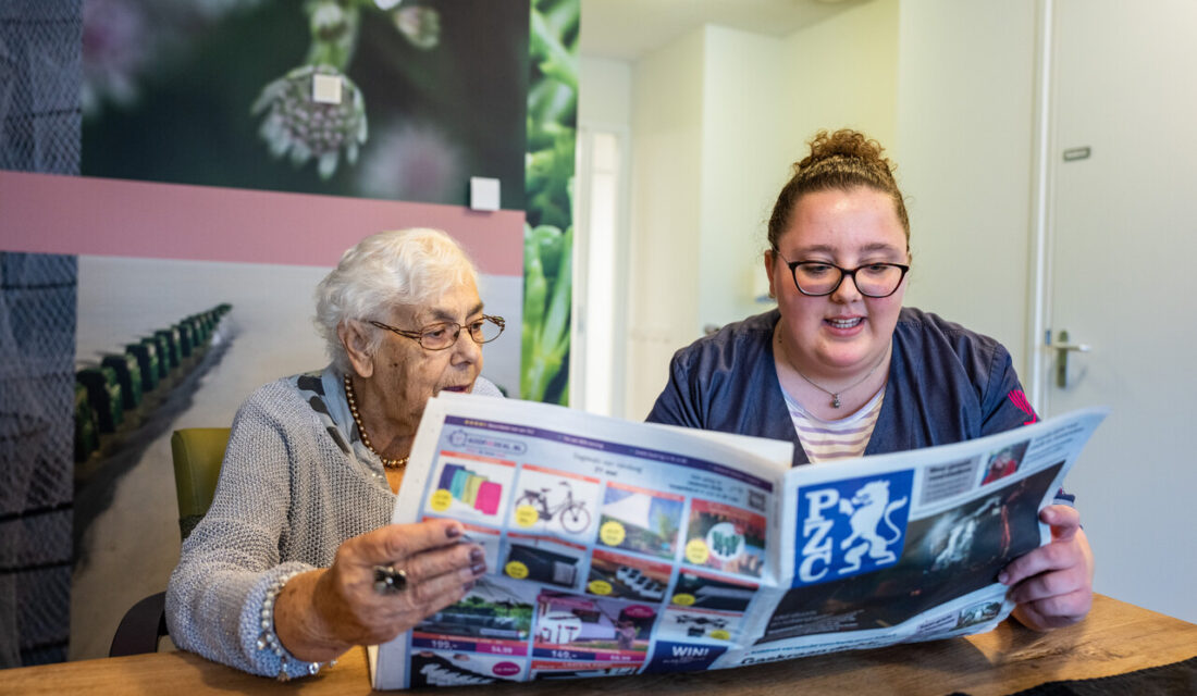 Medewerker leest krant voor aan cliënt