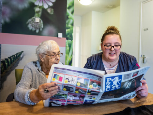 Medewerker leest krant voor aan cliënt