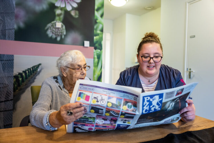 Medewerker leest krant voor aan cliënt