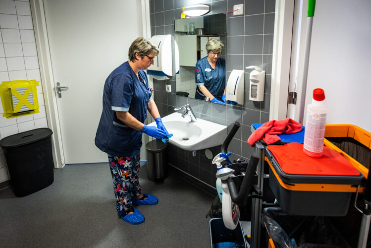 Medewerker maakt een badkamer schoon