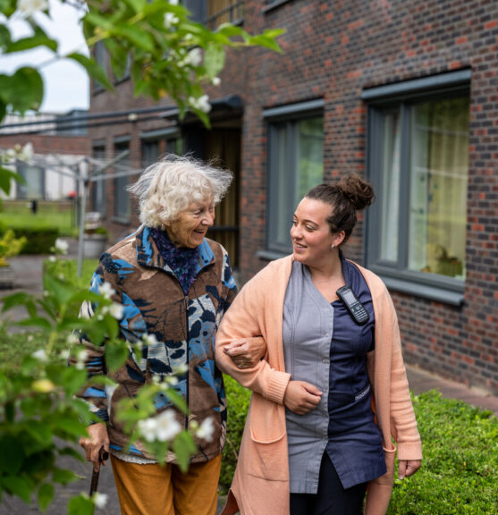 Medewerker en cliënte aan het wandelen in de tuin