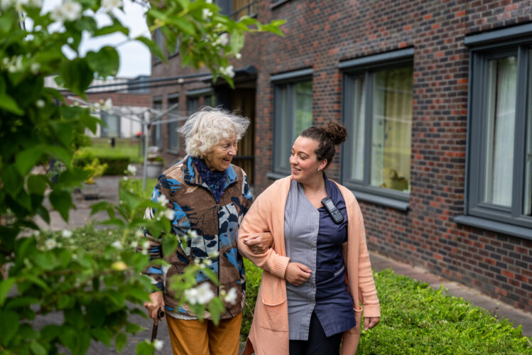 Medewerker en cliënte aan het wandelen in de tuin