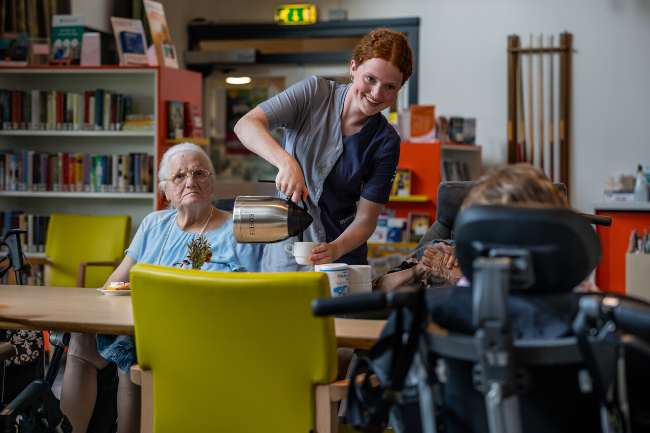 Een medewerker schenkt koffie in voor cliënten