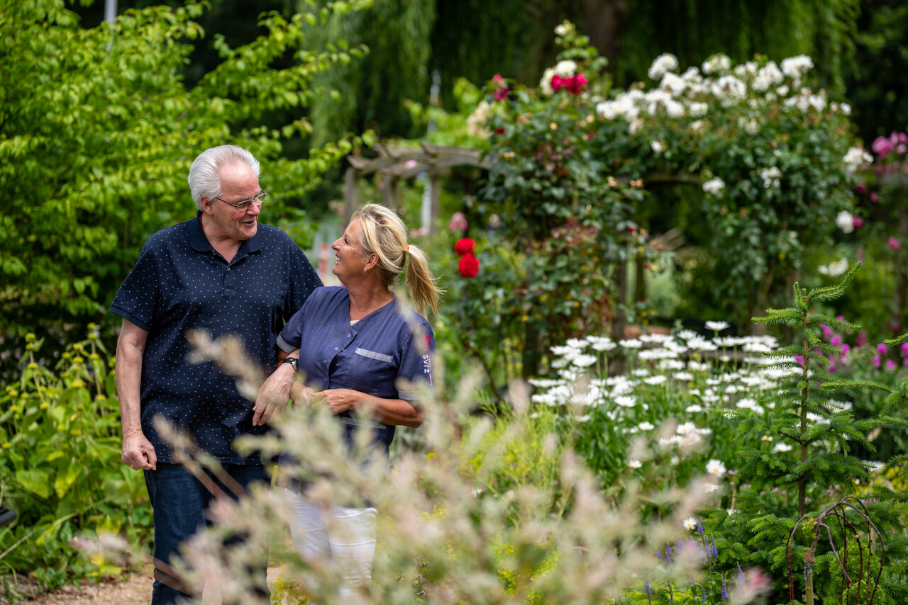 Een medewerker en cliént wandelen samen in de tuin bij SVRZ Thibautstraat in Middelburg