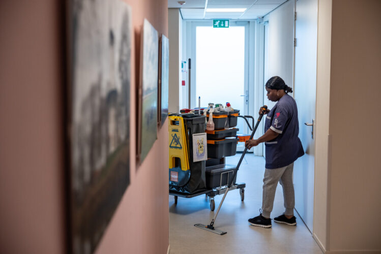 Dame achter schoonmaak kar maakt vloer schoon